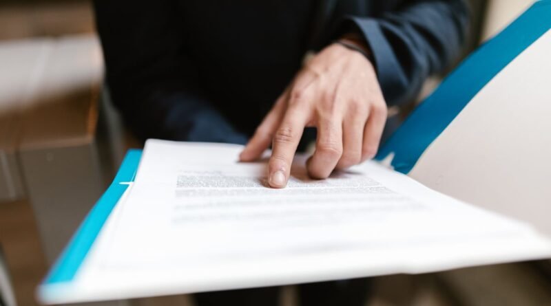 A finger pointing at printed text, illustrating a comparison of free AI tools and their tiers