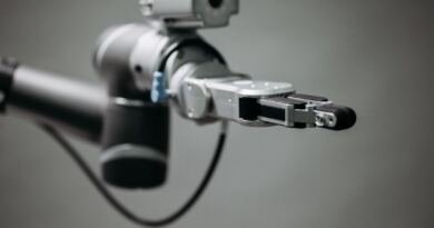 Close-up of a silver and black robotic arm with an open gripper, illustrating the best AI for coding benchmark comparisons.