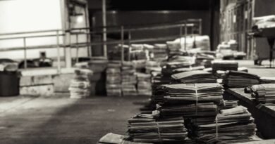 Stacks of folded newspapers in a warehouse, illustrating a reading stack for ai for news updates