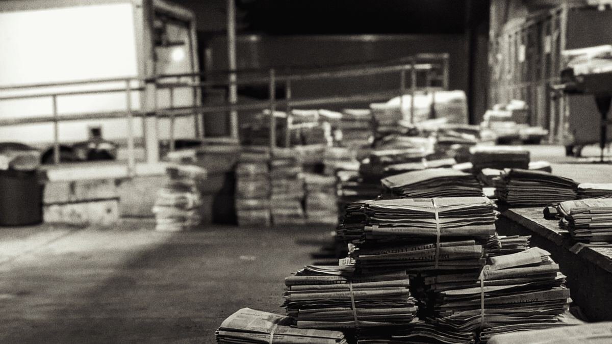 Stacks of folded newspapers in a warehouse, illustrating a reading stack for ai for news updates