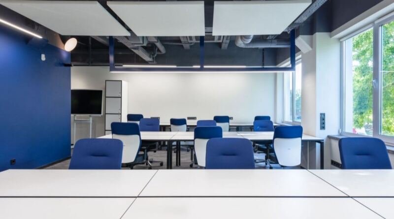 Empty blue chairs and white desks in a bright, unoccupied meeting room, the unfilled seats at the centre of the future of AI at work