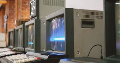 A row of vintage CRT computer terminals, illustrating the history of AI from the 1955 Dartmouth proposal to today.