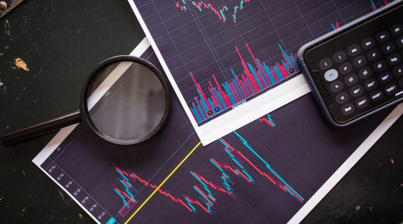 A magnifying glass and pocket calculator on printed stock market charts, illustrating how to read an ai startup funding round.
