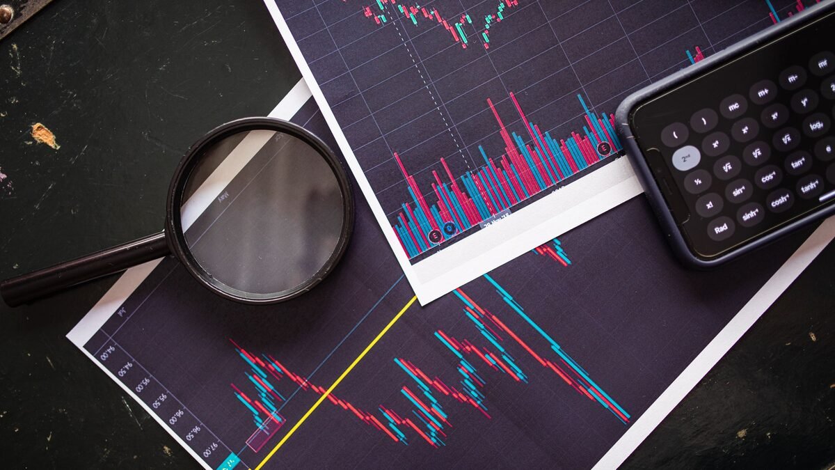 A magnifying glass and pocket calculator on printed stock market charts, illustrating how to read an ai startup funding round.