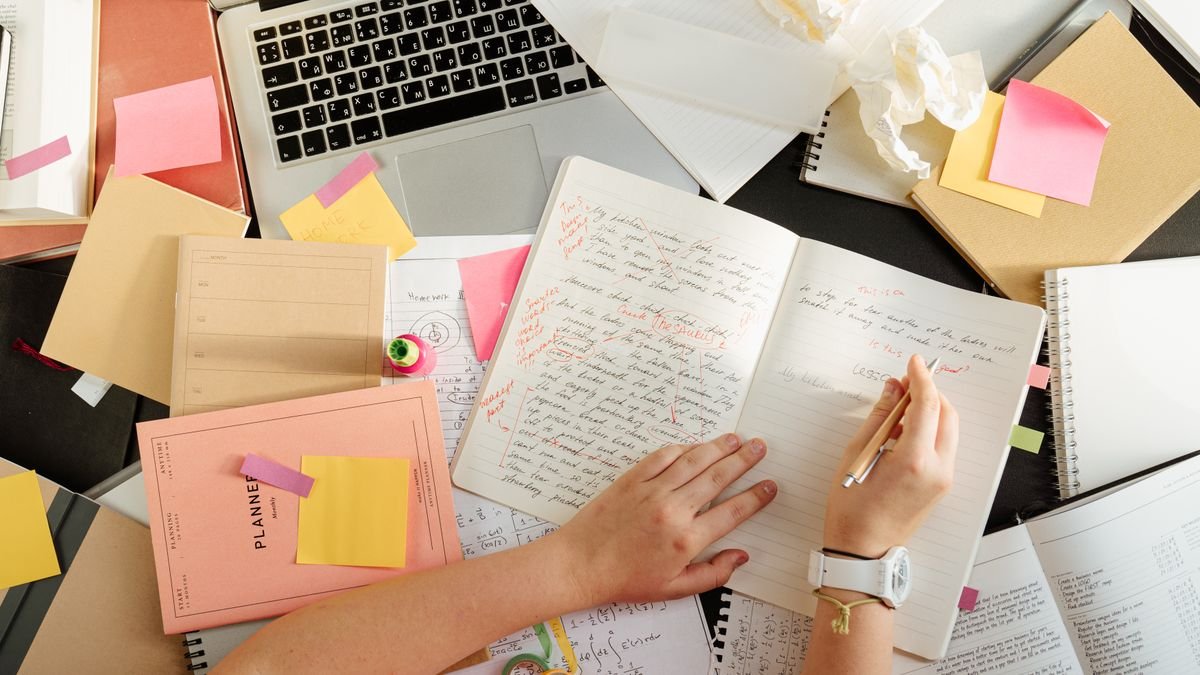 Overhead view of a desk with notebooks, handwritten study notes and an open laptop, illustrating how to learn artificial intelligence.