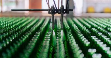 Automated bottling line with robotic nozzles, the kind of factory machinery Anthropic's Model Hardware Standard lets AI agents run