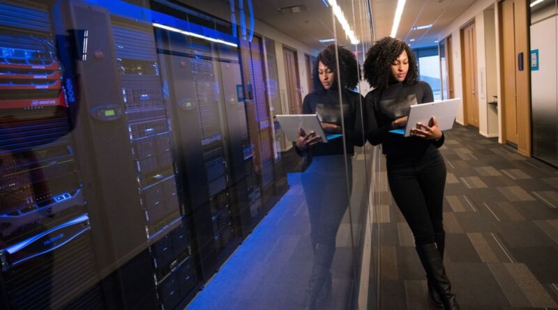 A woman with a laptop in a mirrored data centre, where AI stack economics are decided