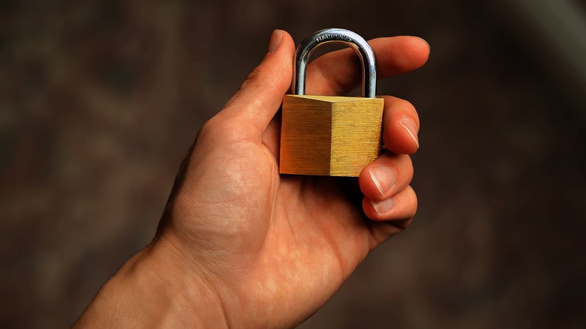 A hand holding a brass padlock, the deletion promised by the right to be forgotten in AI