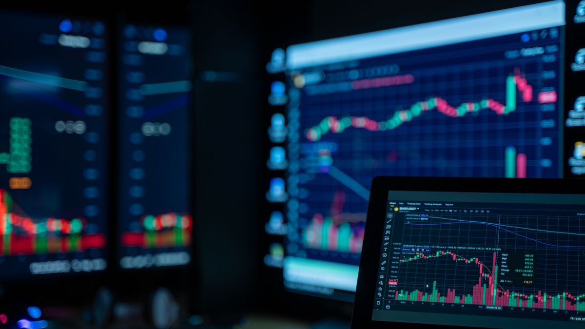 Stock market charts on monitors in a dim room, the figures behind an AI valuation