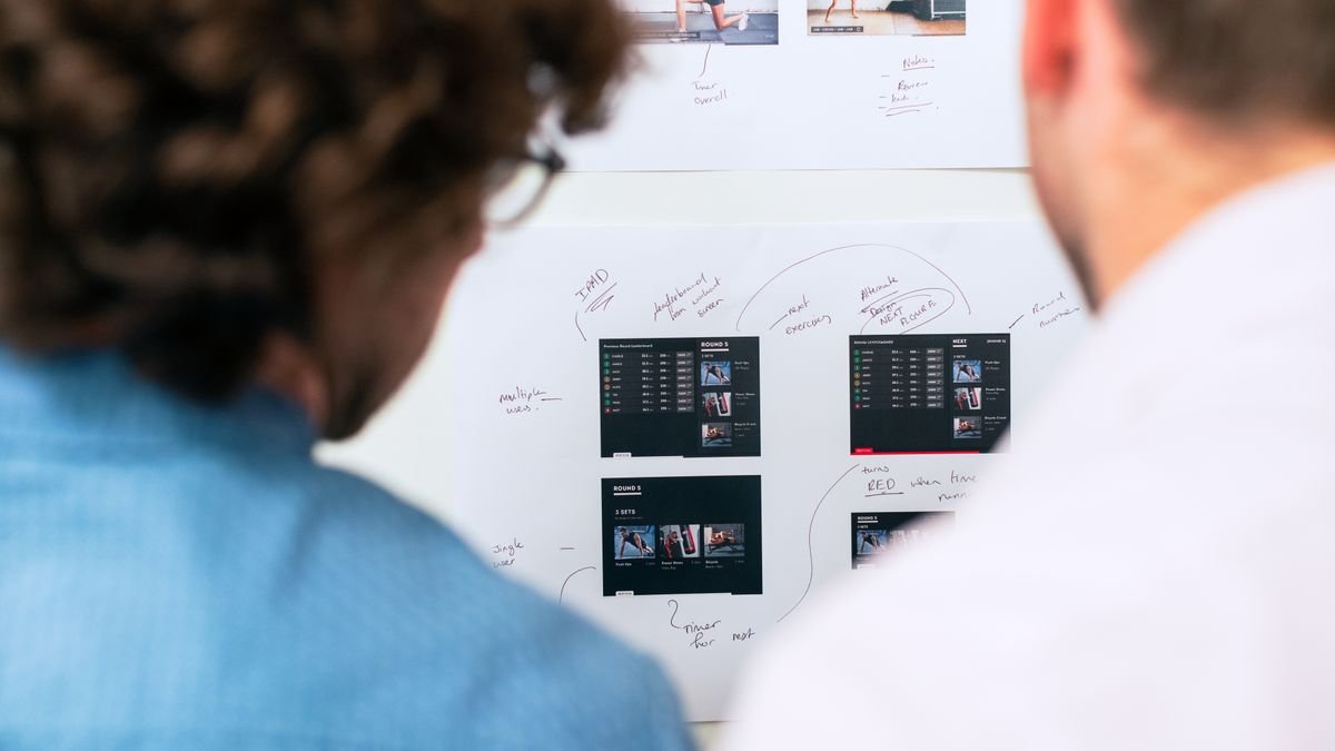 Two professionals planning at a whiteboard, choosing between prompting vs RAG vs fine tuning