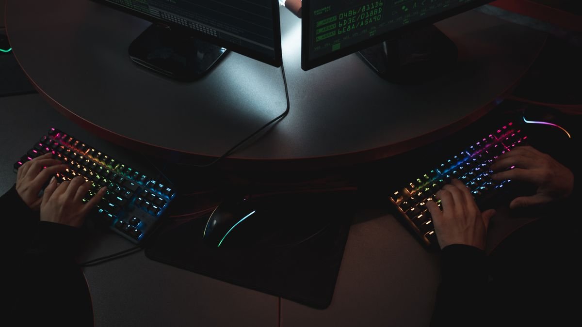 Two people typing on backlit keyboards, the work an OpenAI cyber defence model is built for