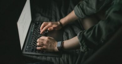 Hands typing on a laptop in low light, the human feedback stage in how RLHF works