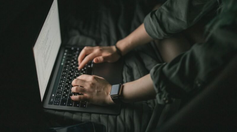 Hands typing on a laptop in low light, the human feedback stage in how RLHF works