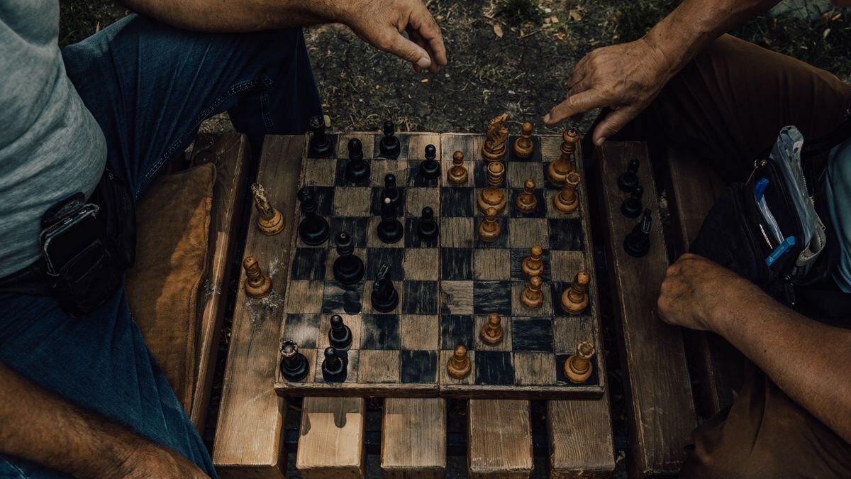 Two people mid chess match outdoors, the deliberation that test time compute pays for