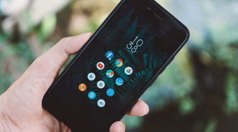 A hand holding a smartphone showing app icons, as Microsoft Copilot apps merge into one