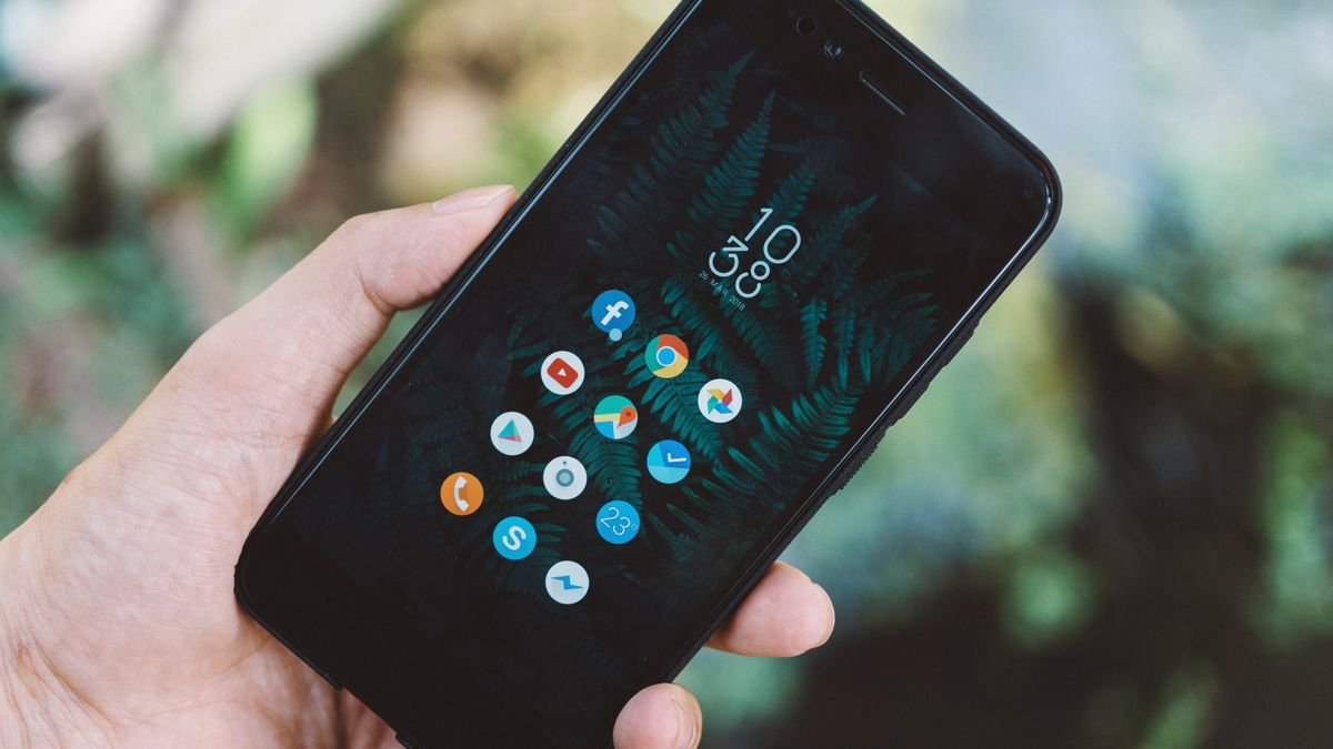A hand holding a smartphone showing app icons, as Microsoft Copilot apps merge into one