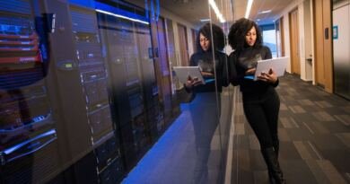 An engineer holds a laptop beside a lit server room, weighing an artificial intelligence platform seat against running the GPU itself.