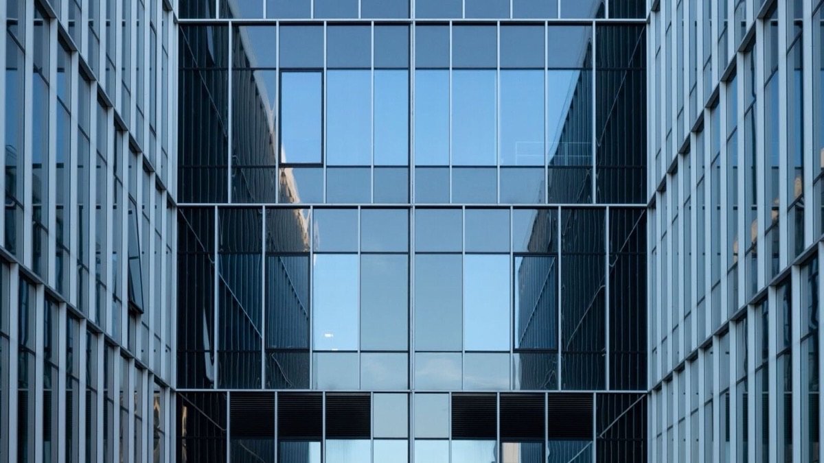 Two glass office towers reflecting a clear blue sky, illustrating enterprise artificial intelligence reaching production.