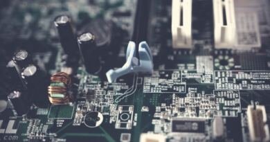 Macro photo of a green computer motherboard with capacitors, a copper coil and white expansion slots
