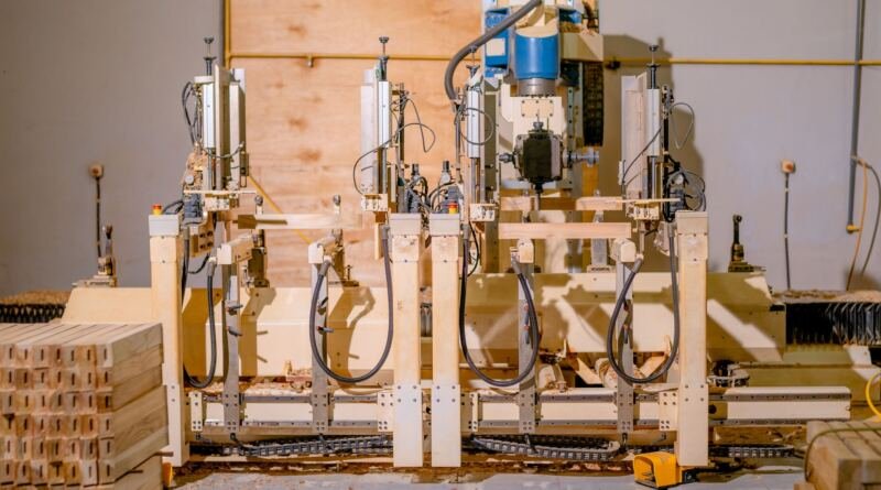 Automated woodworking machine drilling stacked timber parts in a small workshop