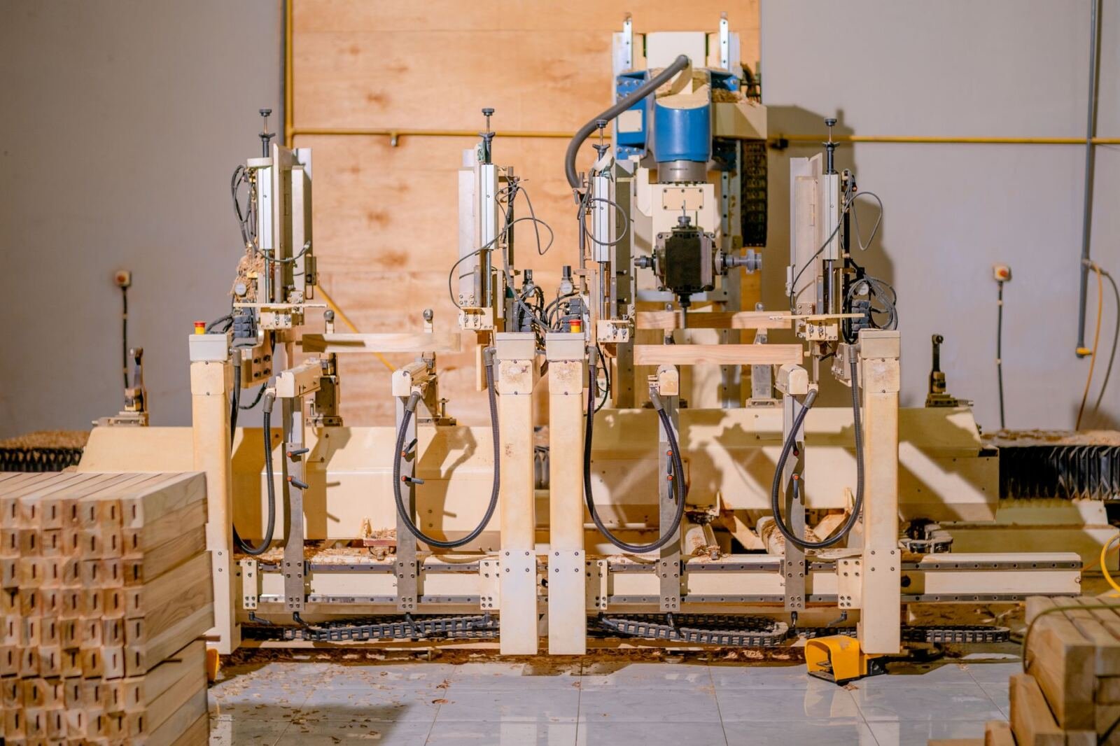 Automated woodworking machine drilling stacked timber parts in a small workshop