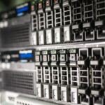 Close-up of stacked rack-mounted servers, rows of drive bays with green and orange status lights glowing along the front panels