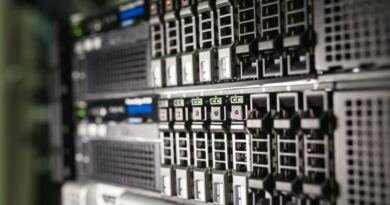 Close-up of stacked rack-mounted servers, rows of drive bays with green and orange status lights glowing along the front panels