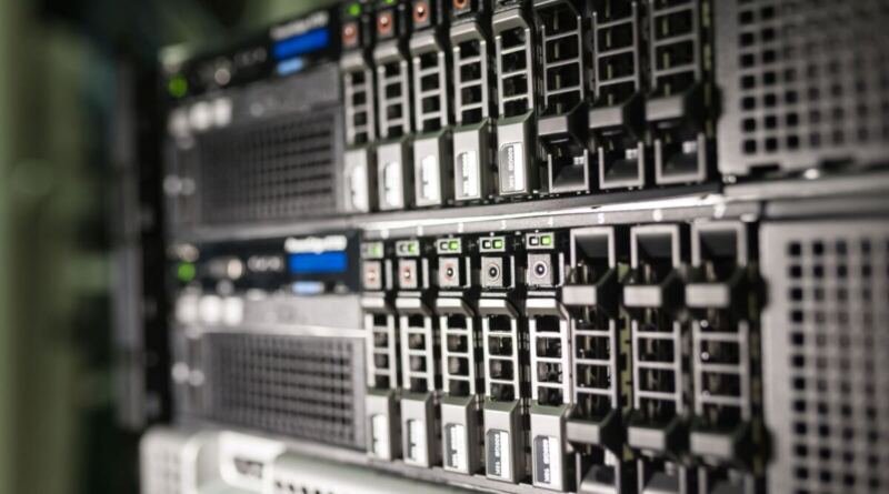Close-up of stacked rack-mounted servers, rows of drive bays with green and orange status lights glowing along the front panels