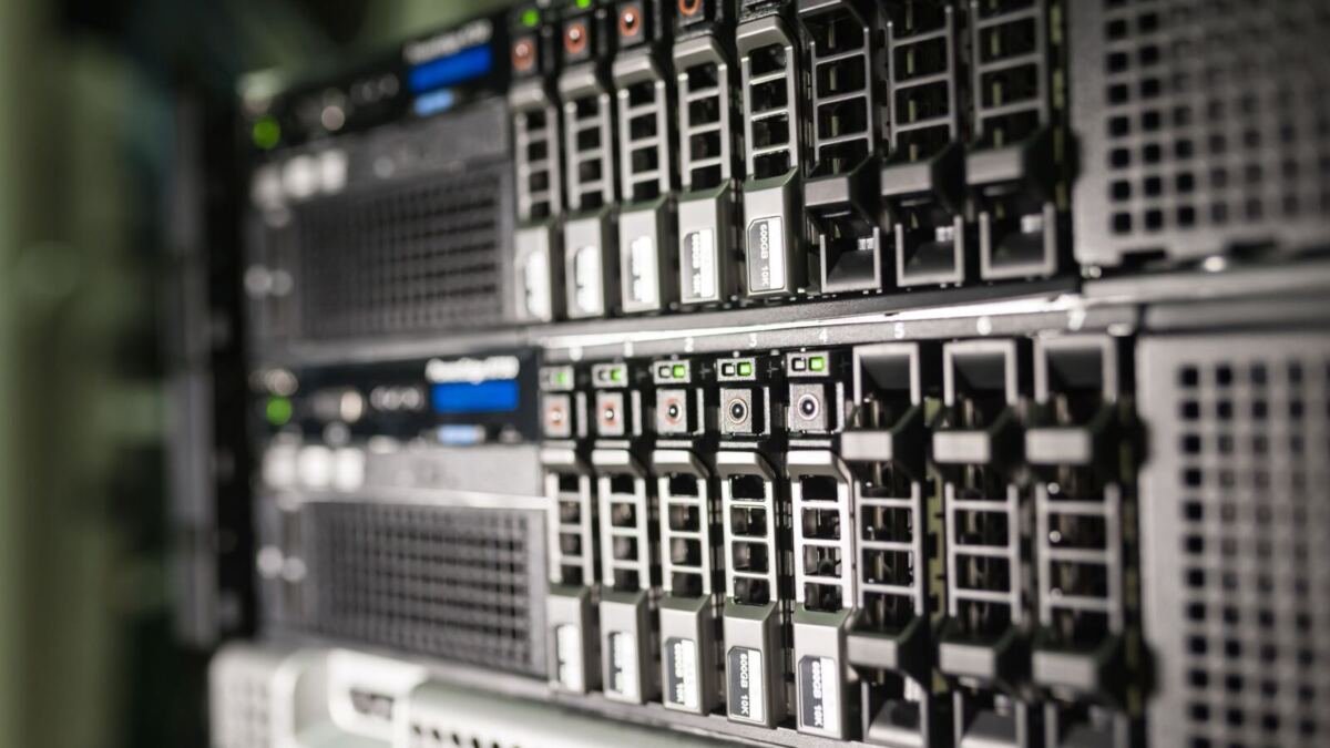 Close-up of stacked rack-mounted servers, rows of drive bays with green and orange status lights glowing along the front panels