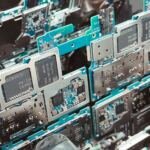 Close-up of stacked green smartphone circuit boards with silver metal shielding cans and Qualcomm and SK hynix chips