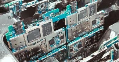 Close-up of stacked green smartphone circuit boards with silver metal shielding cans and Qualcomm and SK hynix chips