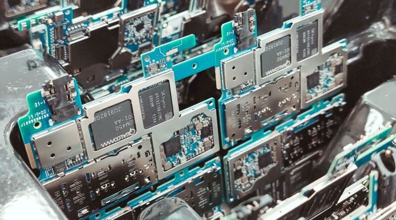 Close-up of stacked green smartphone circuit boards with silver metal shielding cans and Qualcomm and SK hynix chips