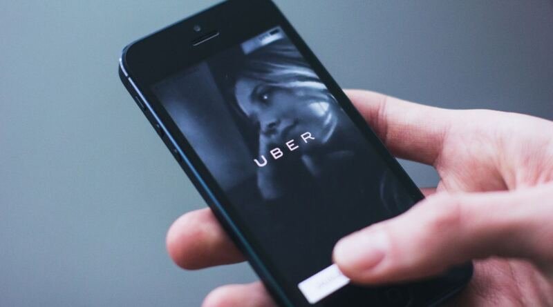 A hand holding a smartphone displaying the Uber app launch screen, the subject of the Dutch regulator's Uber GDPR fine