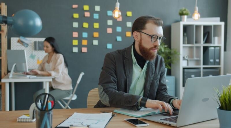 Young professionals working at desks in a modern open-plan office, illustrating artificial intelligence and business use by function