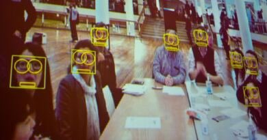 Projected camera feed showing yellow face-detection boxes over some but not all of the people seated at a long table, illustrating AI bias in facial analysis