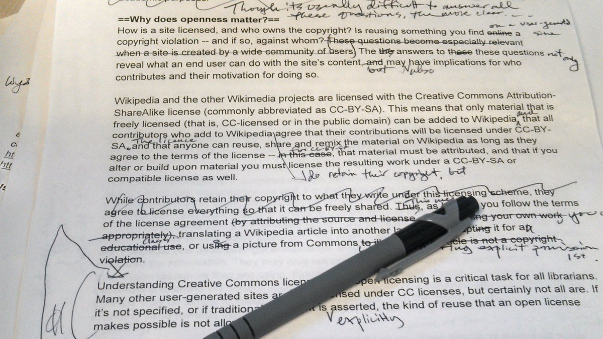 Printed manuscript page covered in handwritten pen corrections and margin notes, with a ballpoint pen lying across it, illustrating the editing work AI in content creation leaves behind