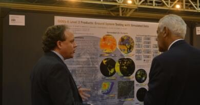 Two researchers in suits discussing a printed scientific poster at a conference poster session, illustrating where ai research news starts before any peer review