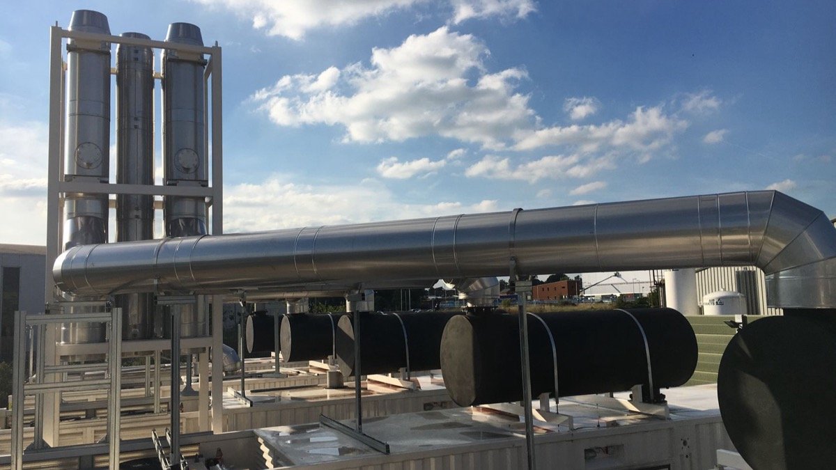 Insulated steel exhaust ducting and black fuel tanks on a rooftop generator plant, illustrating the compute behind the Reflection AI Beam model