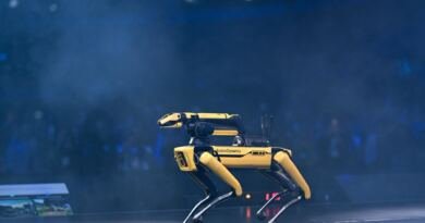 Yellow Boston Dynamics Spot quadruped robot on a dark stage, illustrating the FieldAI $700M term sheet