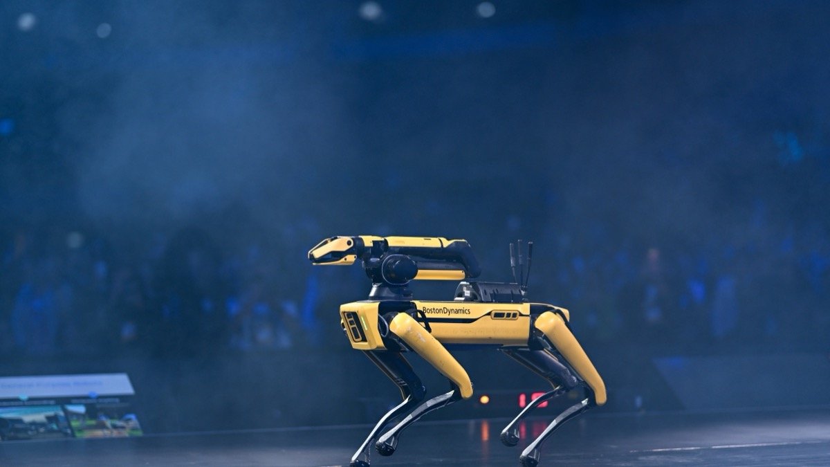Yellow Boston Dynamics Spot quadruped robot on a dark stage, illustrating the FieldAI $700M term sheet