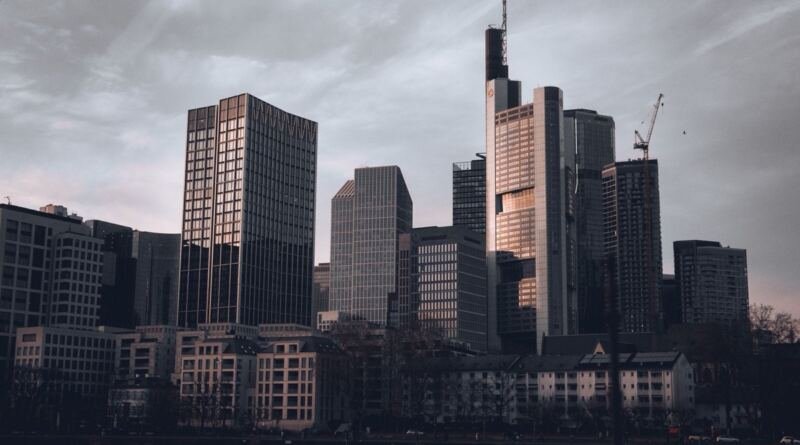 Grey office towers and a construction crane at dusk, illustrating the Isomorphic Labs valuation talks