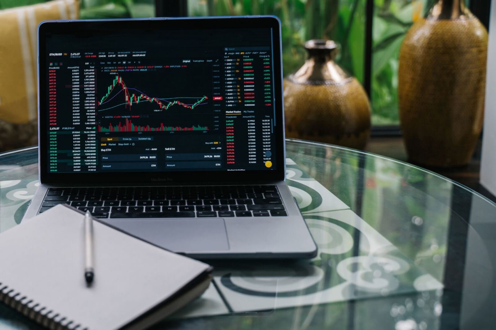 Laptop on a glass table showing a candlestick trading chart, illustrating the OpenAI Orchestra Bio acquisition
