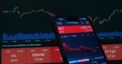 Smartphone showing a stock trading app against a red candlestick chart, illustrating the Lyft driver settlement