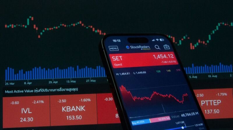 Smartphone showing a stock trading app against a red candlestick chart, illustrating the Lyft driver settlement