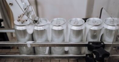 Aluminium drink cans on a factory conveyor line, illustrating the Nous Research $90M round