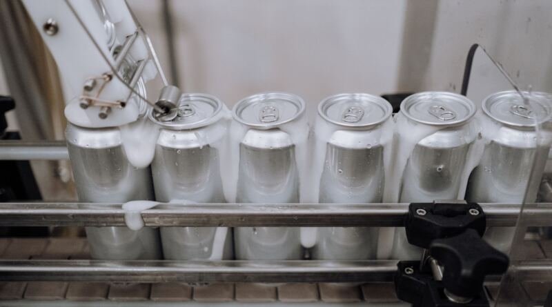 Aluminium drink cans on a factory conveyor line, illustrating the Nous Research $90M round