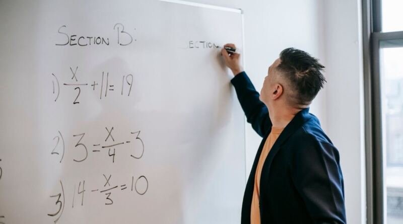 A man in a blazer writing algebra on an office whiteboard, illustrating the open letter from the fired OpenAI safety researchers